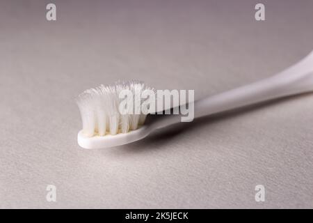 Gros plan sur une vieille brosse à dents sur fond blanc. Les poils de la brosse à dents sont usés. Banque D'Images