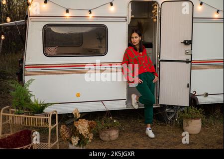Une femme caucasienne en pull tricoté rouge surdimensionné voyage à motorhome en automne. Banque D'Images