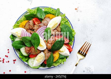 Salade Périgord avec foie de poulet, tomates, concombres, œufs, laitue et épinards. Arrière-plan blanc de la table de cuisine, vue du dessus Banque D'Images