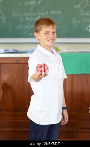 Animaux de compagnie des enseignants. Un jeune écolier mignon tenant une pomme dans la salle de classe. Banque D'Images