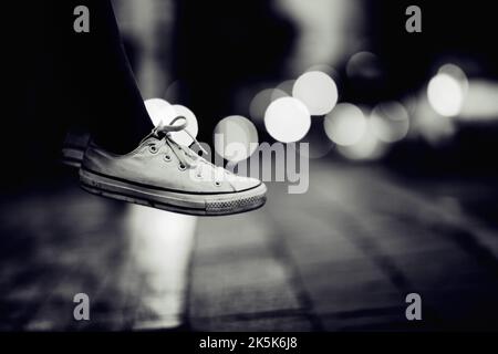 Vol stationnaire dans l'air. Image rognée d'une personne portant des baskets qui semble survoler une rue. Banque D'Images