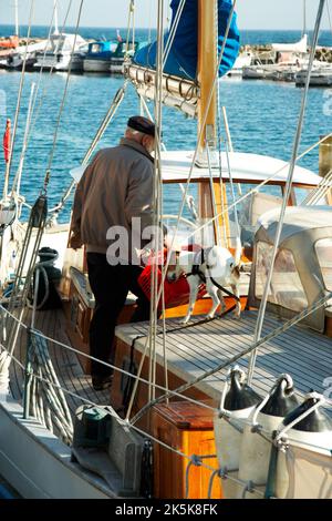 Les compagnons se prépare à un autre voyage. Un homme âgé et son chien debout dans un bateau encombré. Banque D'Images
