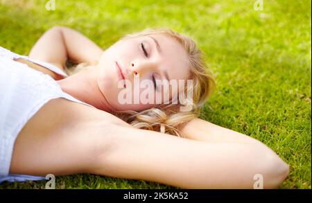 Juste un coup de chat rapide. Jeune femme prenant un peu de temps pour avoir un chat nap à l'extérieur dans son jardin. Banque D'Images