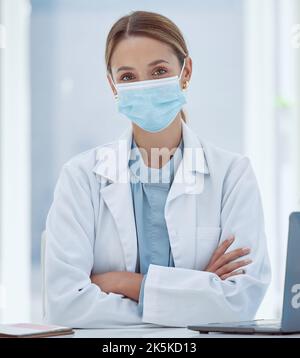 Masque facial, covid et portrait d'un médecin dans son bureau à l'hôpital pendant une pandémie. Coronavirus, femme et professionnel de la santé assis Banque D'Images