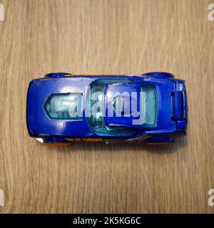 La vue de dessus d'une voiture de jouet bleu Mattel Hot Wheels sur une surface en bois Banque D'Images