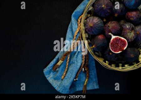 Figues dans un panier de paille avec serviette bleue. Banque D'Images