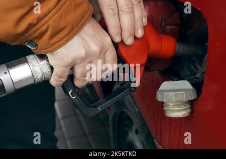 Un homme ravitaille une voiture. Il sort la buse de ravitaillement en carburant du réservoir et ferme le bouchon du réservoir de la voiture. Banque D'Images