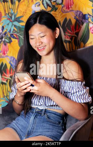 femme utilisant un téléphone portable assis dans un fauteuil Banque D'Images