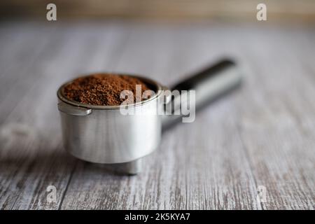 Porte-filtre rempli de café moulu sur table grise Banque D'Images