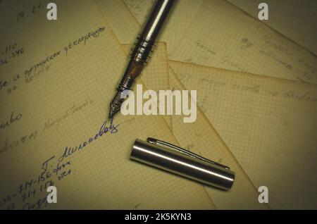 Vue de dessus d'un stylo plume d'argent sur les feuilles de papier manuscrites Banque D'Images