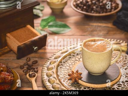 Tasse de café chaud placée avec des grains de café rôtis, des dattes fraîches et du café moulu sur fond de bois rustique. Banque D'Images