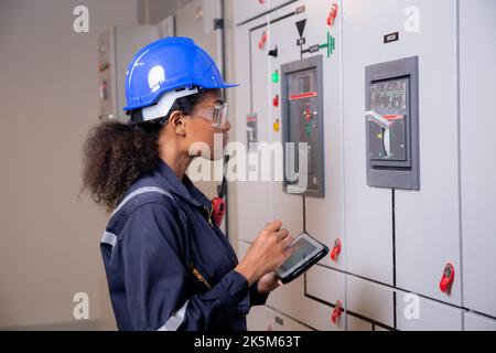 Electricité jeune femme asiatique ingénieur examinant le système d'armoire de maintenance électrique et utilisant une tablette dans la salle de contrôle à l'usine industrielle, technicien Banque D'Images