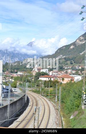 Vue panoramique de la ville en automne avec montagnes et vallée urbanisée avec réseaux de chemin de fer et d'électricité et château médiéval au loin. Banque D'Images