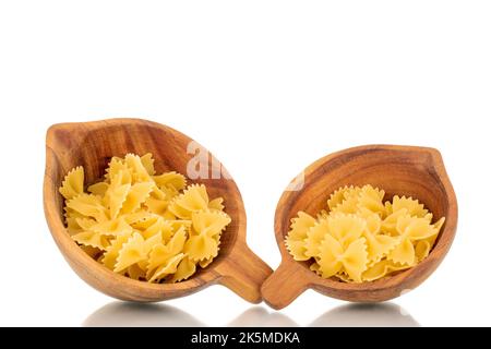 Plusieurs macaroni de papillon cru dans deux tasses en bois, macro, isolé sur fond blanc. Banque D'Images