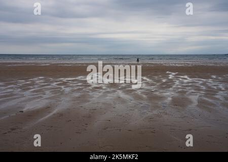 Seul un petit groupe de personnes marchent au bord de la mer à Oxwich Bay dans un après-midi froid et lamentable de septembre. Banque D'Images