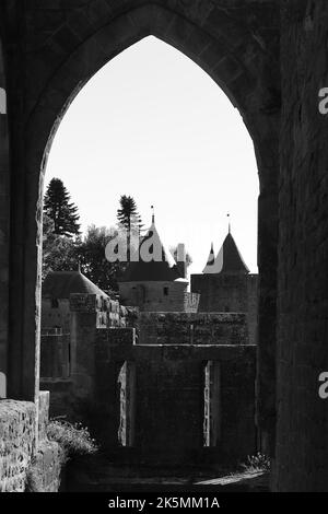 Vue sur la citadelle médiévale de Carcassonne par une porte voûtée. Les tours fortifiées et les murs de pierre du site du patrimoine mondial de l'UNESCO. Banque D'Images