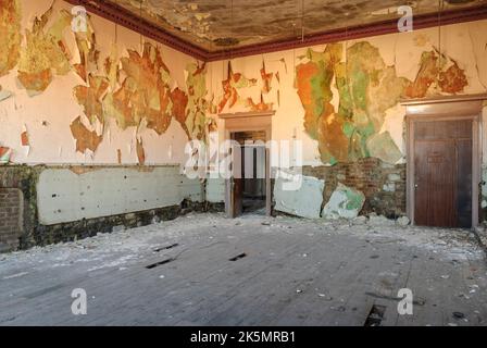 Plâtre tombant des murs d'un bâtiment abandonné avec de hauts plafonds. Banque D'Images