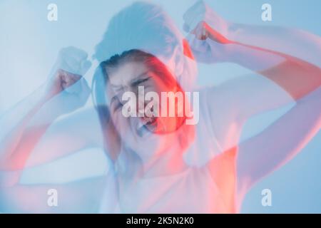 Crise nerveuse. Troubles mentaux. Anxiété colère. Double exposition flou silhouette de la femme folle frustrée hurlant dans la lumière rouge néon de couleur isolée Banque D'Images