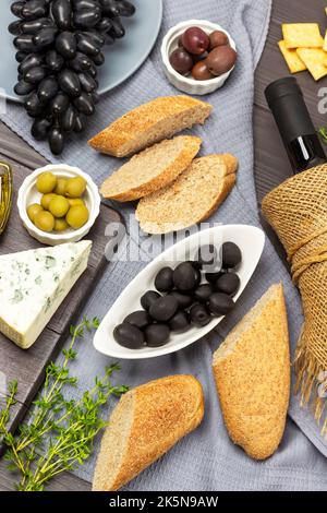 Apéritif avec olives, fromage, baguette et vin rouge. Pose à plat. Arrière-plan en bois sombre. Banque D'Images