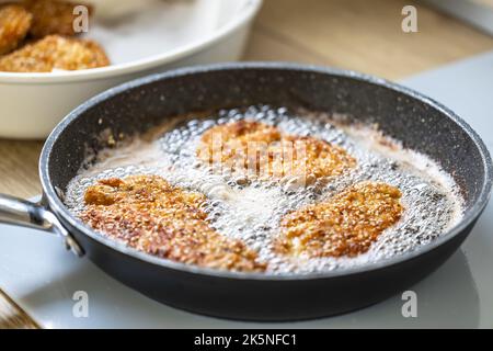 Dans une poêle sombre, faire revenir de l'huile chaude avec du schnitzel. Banque D'Images