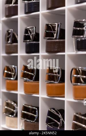 Différentes ceintures en cuir de couleur sont exposées sur l'étagère dans une boutique de vêtements pour hommes. Faible profondeur de champ. Mode et vêtements Banque D'Images