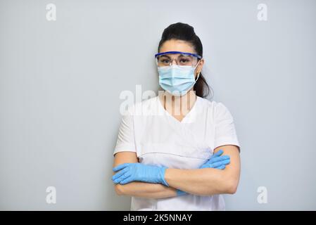 Femme adorable dentiste en uniforme, lunettes de protection et masque facial. Banque D'Images