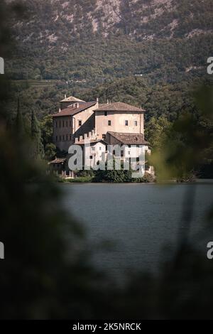 Une photo verticale d'un vieux château entouré de montagnes verdoyantes avec un lac en premier plan Banque D'Images