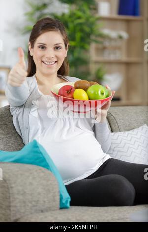 la femme tient les fruits dans un bol tout en montrant le pouce vers le haut Banque D'Images