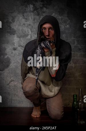 Homme de cheveux noir avec une bouteille d'alcool près de vieux mur de brique Banque D'Images