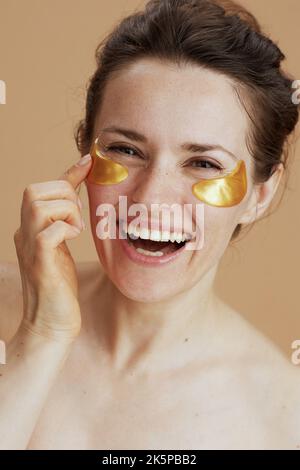 femme moderne souriante avec des taches d'oeil sur fond beige. Banque D'Images