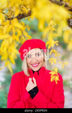 Excitée femme gracieuse souriant dans le parc d'automne à la lumière du soleil Banque D'Images