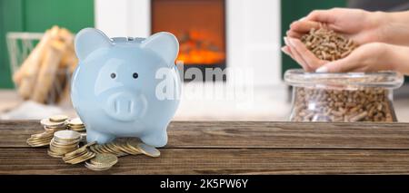 Table en bois avec banque de porc, pièces de monnaie et femme avec des granules à la maison. Concept de saison de chauffage Banque D'Images