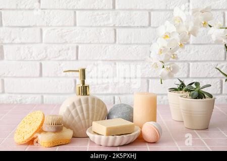 Ensemble de fournitures de bain avec des plantes de maison sur la table près du mur de briques légères Banque D'Images