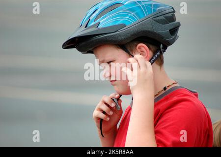 10 ans mettant un casque de vélo pour se protéger contre les blessures à la tête pendant la conduite à vélo Banque D'Images