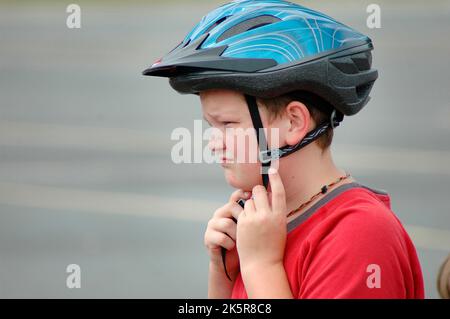 10 ans mettant un casque de vélo pour se protéger contre les blessures à la tête pendant la conduite à vélo Banque D'Images