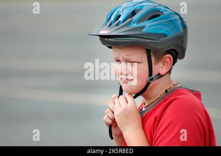 10 ans mettant un casque de vélo pour se protéger contre les blessures à la tête pendant la conduite à vélo Banque D'Images