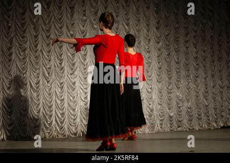 Danse espagnole. Filles dansant dans des robes noires. Leçon de danse. Traditions espagnoles. Vêtements rouges. Danseurs sur scène. Banque D'Images