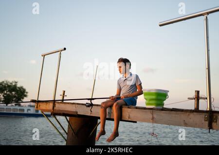 Pêche des enfants sur le lac. Enfant pêcheur garçon avec une tourniquet à la rivière. pêche de garçon. Banque D'Images