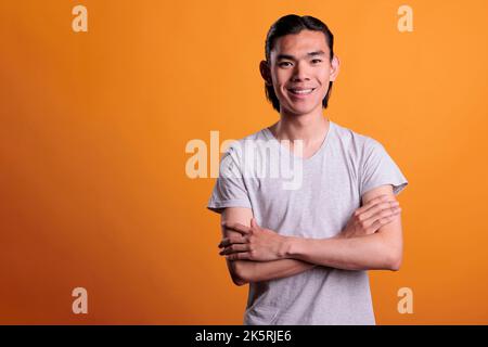 Souriant homme asiatique heureux avec bras croisés portrait, vue de face. Adolescent joyeux debout avec l'expression du visage positive regardant la caméra, belle personne joyeuse moyenne prise de vue Banque D'Images