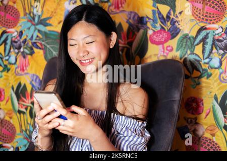femme utilisant un téléphone portable assis dans un fauteuil Banque D'Images