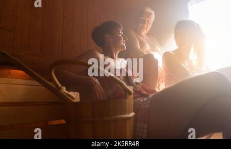 Trois personnes heureuses dans un sauna en conversation Banque D'Images