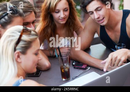 Publier leurs photos en ligne. Groupe d'adolescents qui apprécient les boissons dans un restaurant en plein air avec toute leur technologie moderne. Banque D'Images