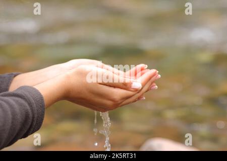 Gros plan d'une femme mains attrapant l'eau fraîche brute de la rivière Banque D'Images