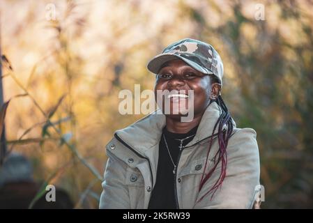 Une femme africaine heureuse avec une casquette dehors dans la belle automne suédoise Banque D'Images