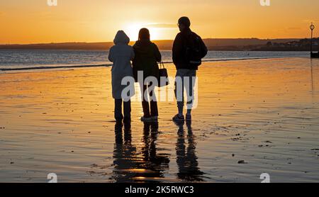 Portobello, Édimbourg, Écosse, Royaume-Uni. 10th octobre 2022. Lever de soleil frais à 9 degrés centigrade pour ceux qui s'aventurer en bord de mer par Firth of Forth pour faire de l'exercice ou tout simplement s'imprégner de la lumière de l'aube. En photo : trois touristes qui se reflètent dans la pluie admirent la couleur de l'aube. Crédit : Arch White/alamy Live News. Banque D'Images