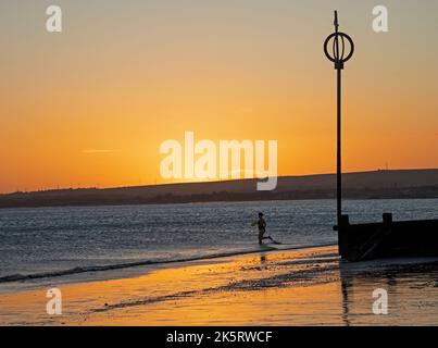 Portobello, Édimbourg, Écosse, Royaume-Uni. 10th octobre 2022. Lever de soleil frais à 9 degrés centigrade pour ceux qui s'aventurer en bord de mer pour faire de l'exercice ou simplement se baigner dans la lumière de l'aube. Une femme se dirige vers le Firth of Forth pour un plongeon froid. Crédit : Arch White/alamy Live News. Banque D'Images