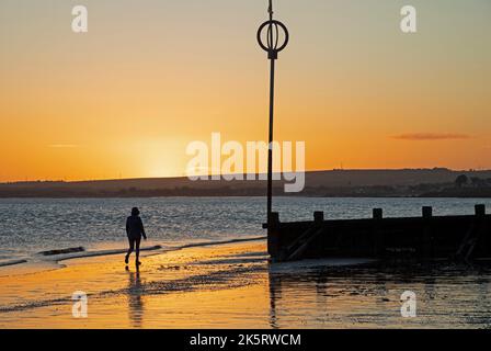 Portobello, Édimbourg, Écosse, Royaume-Uni. 10th octobre 2022. Lever de soleil frais à 9 degrés centigrade pour ceux qui s'aventurer en bord de mer par Firth of Forth pour faire de l'exercice ou tout simplement s'imprégner de la lumière de l'aube. Photo : une femme marche le long du rivage à l'aube. Crédit : Arch White/alamy Live News. Banque D'Images