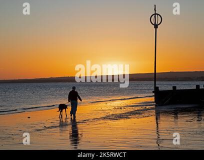 Portobello, Édimbourg, Écosse, Royaume-Uni. 10th octobre 2022. Lever de soleil frais à 9 degrés centigrade pour ceux qui s'aventurer en bord de mer par Firth of Forth pour faire de l'exercice ou tout simplement s'imprégner de la lumière de l'aube. Sur la photo, une femme marche le long du rivage avec son chien. Crédit : Arch White/alamy Live News. Banque D'Images