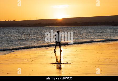 Portobello, Édimbourg, Écosse, Royaume-Uni. 10th octobre 2022. Lever de soleil frais à 9 degrés centigrade pour ceux qui s'aventurer en bord de mer par Firth of Forth pour faire de l'exercice ou tout simplement s'imprégner de la lumière de l'aube. Photo : une femme marche le long du rivage à l'aube. Crédit : Arch White/alamy Live News. Banque D'Images