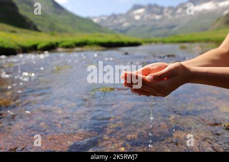 Gros plan d'une femme mains attrapant l'eau de la rivière dans la montagne Banque D'Images